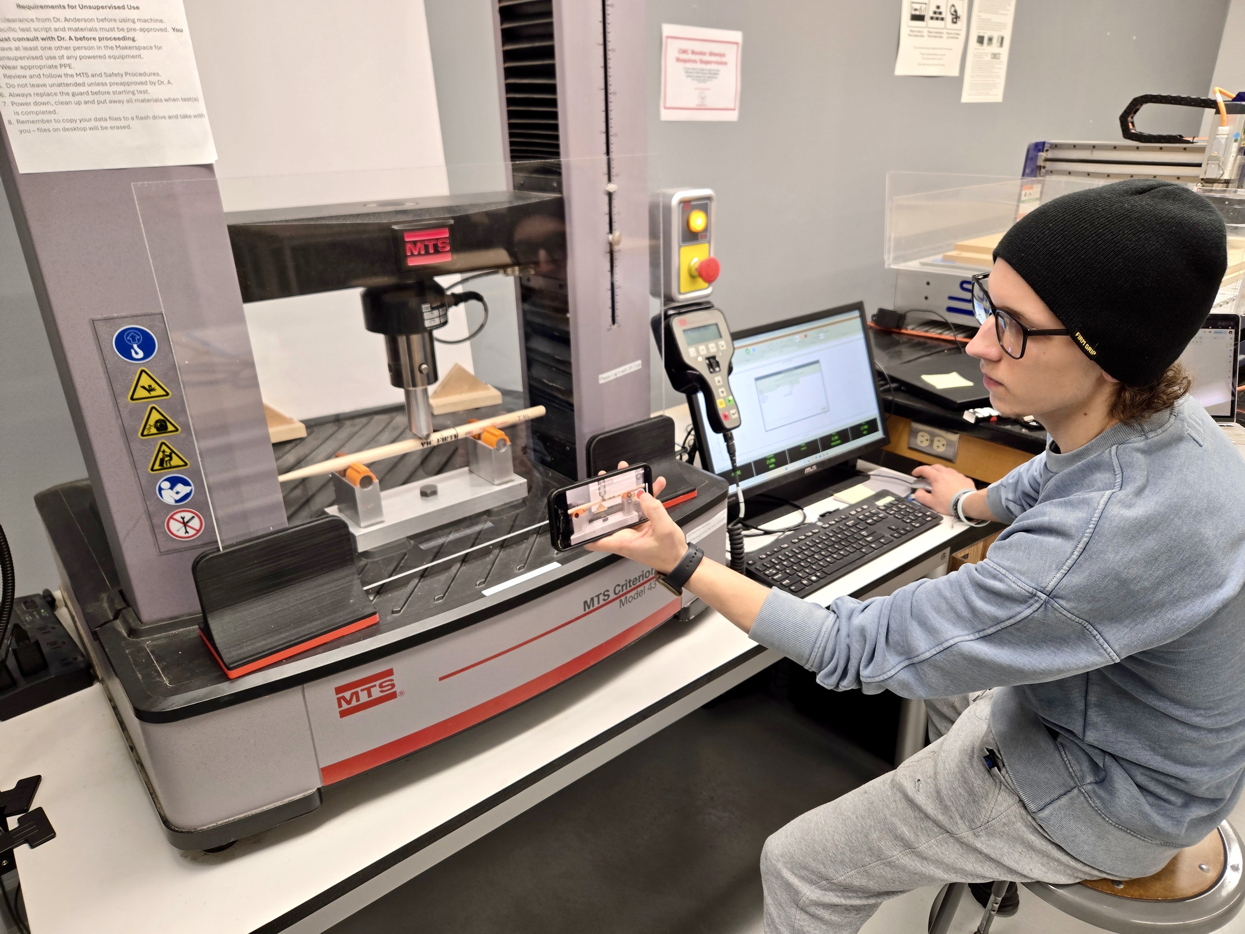 A student testing a specimen with a Materials Testing System machine
