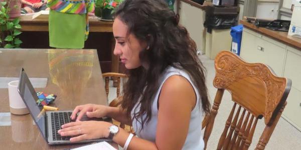 English Major typing on laptop at table in department