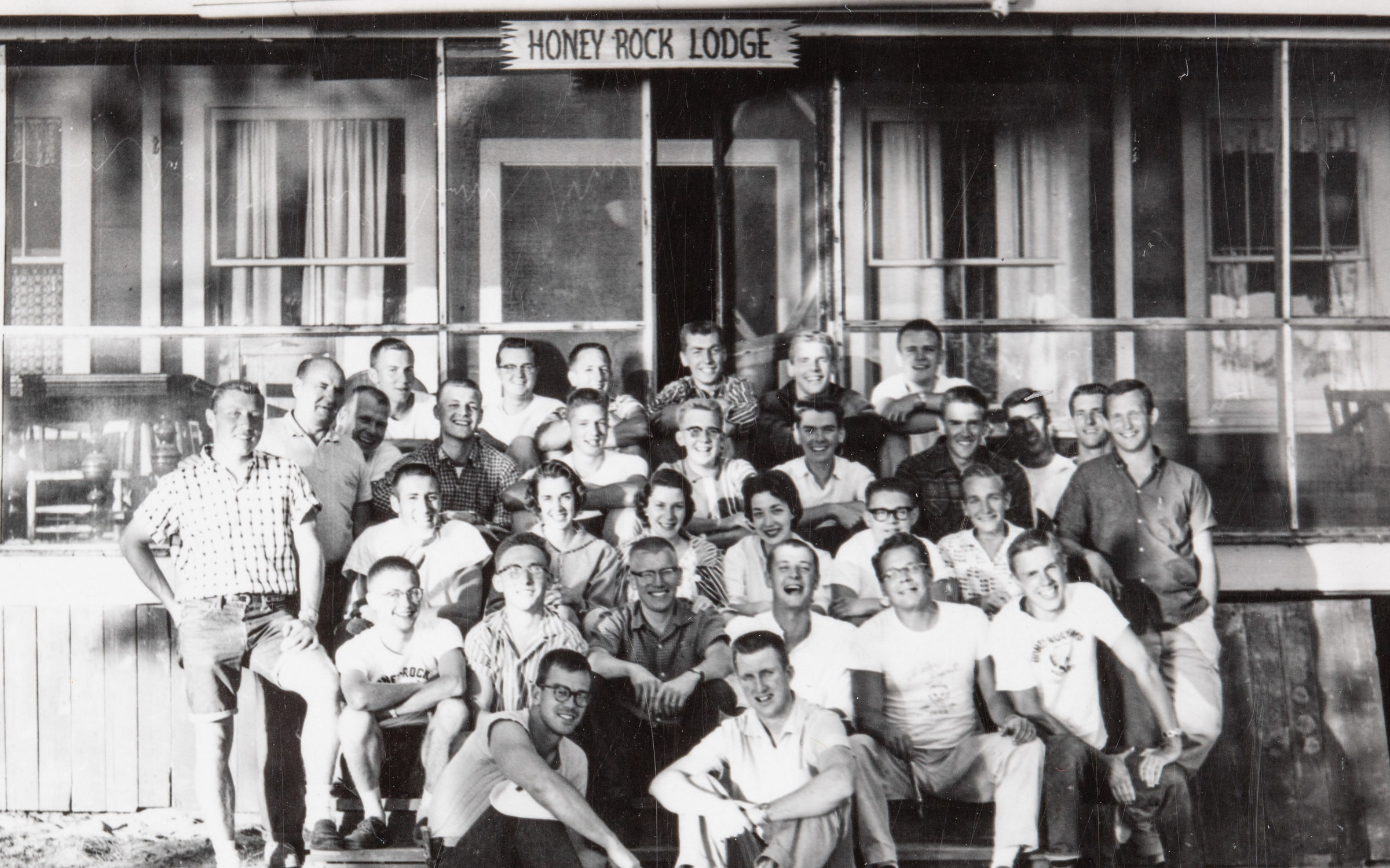 a group of honeyrock students and staff sitting in front of a building