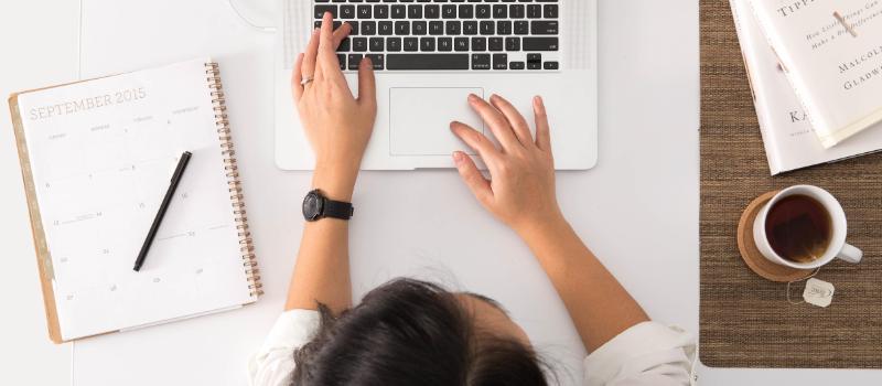 Woman working at computer with coffee and calendar