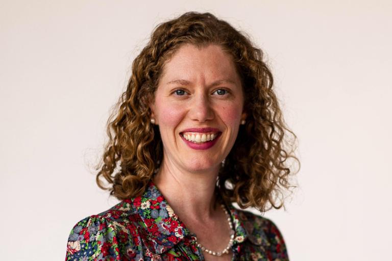 Woman wearing multicolor floral dress holds branded Wheaton insulated mug