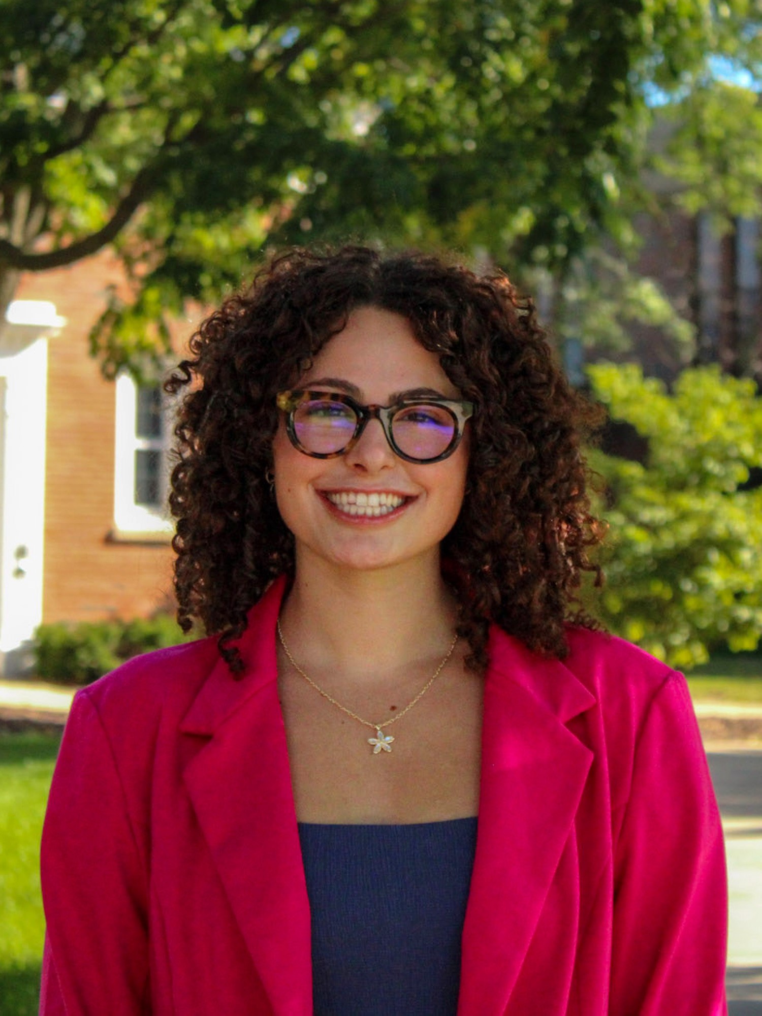 A young woman with curly brown hair smiles