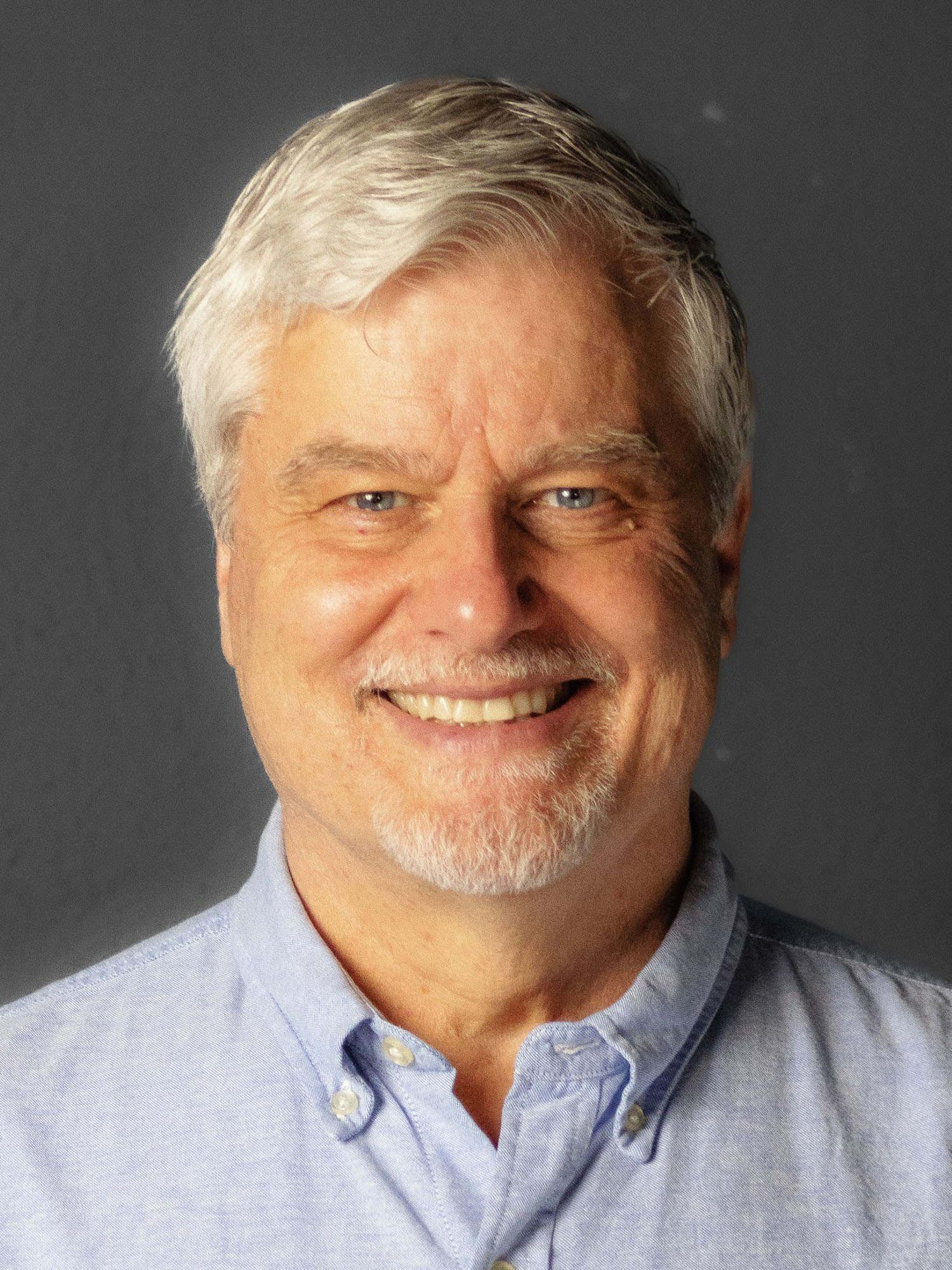 A white man with white hair smiles