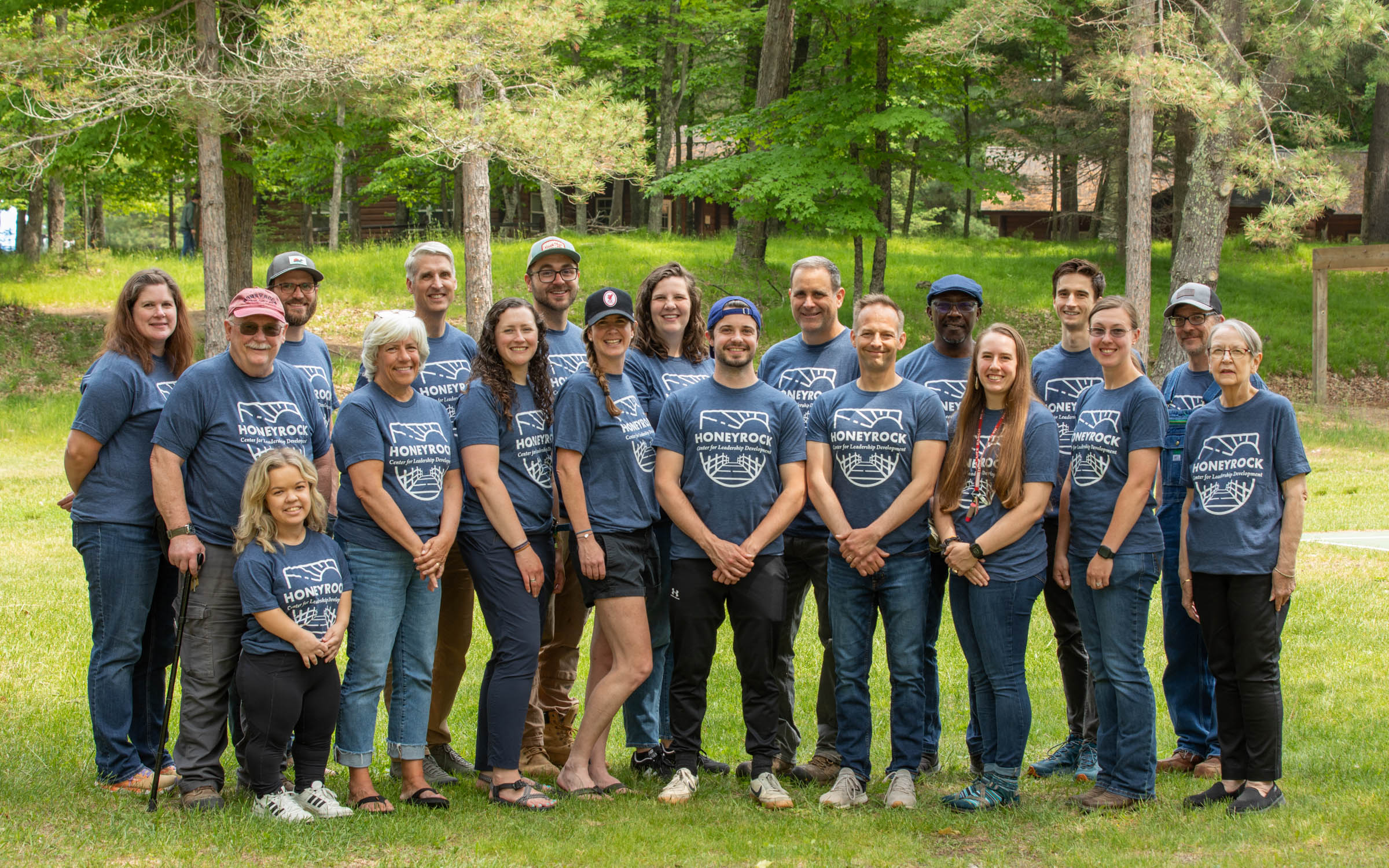 A group of men and women of various ages smile and wear shirts that say HoneyRock on them