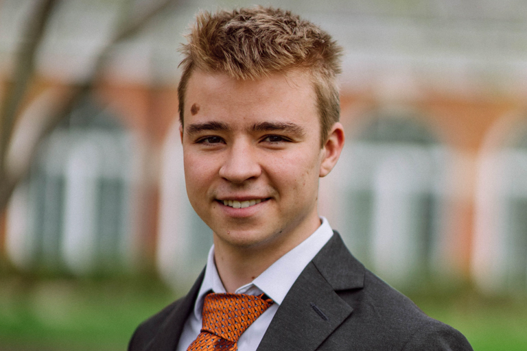 A young white male with light brown hair smiles