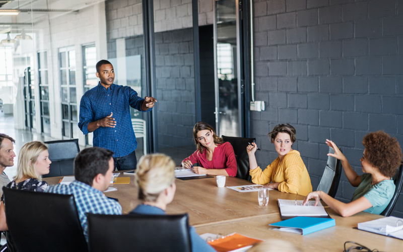 A group of adults sit around a table talking