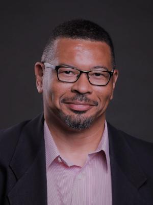A black man wearing glasses smiles