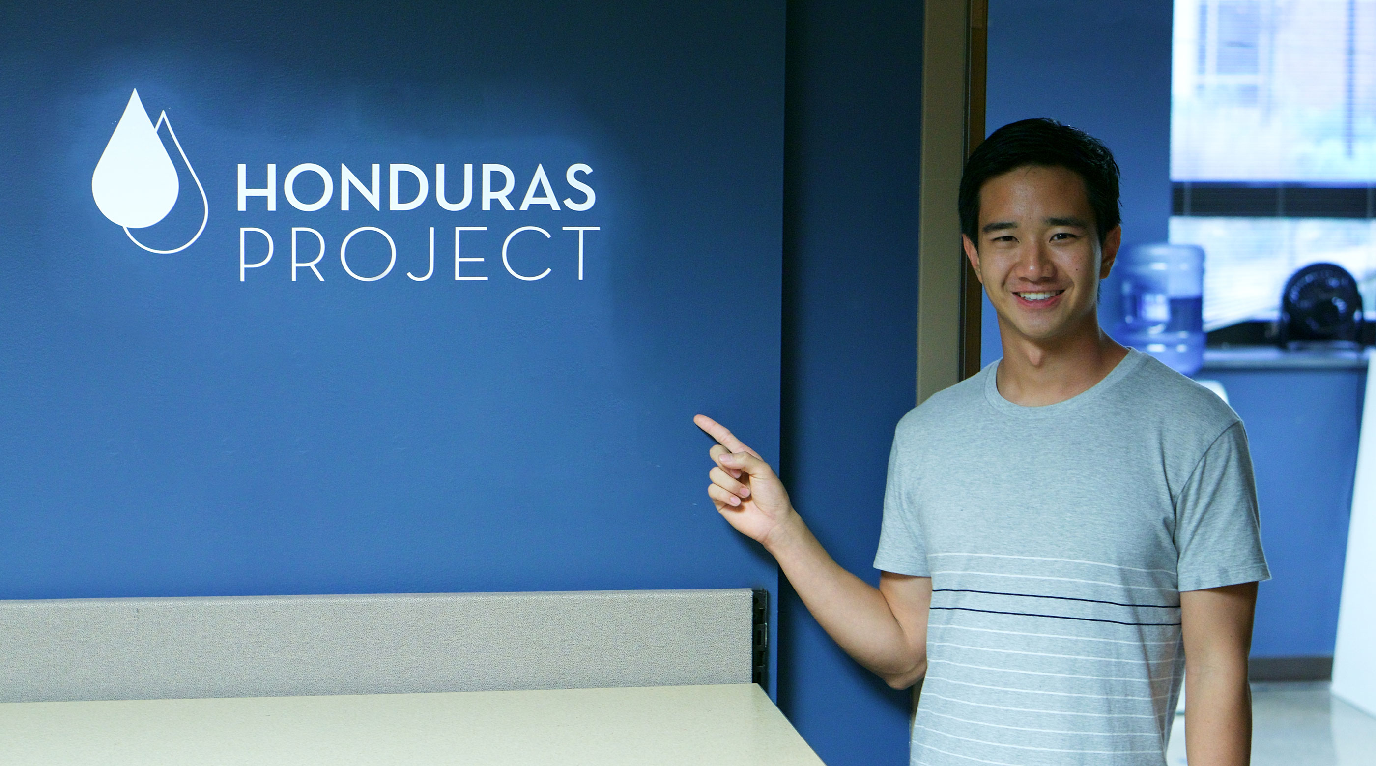 Wheaton Student pointing at Honduras Project Logo 
